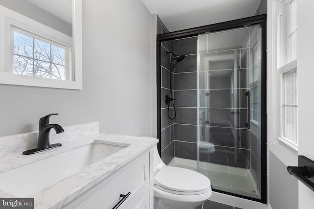 bathroom featuring a shower with shower door, vanity, and toilet