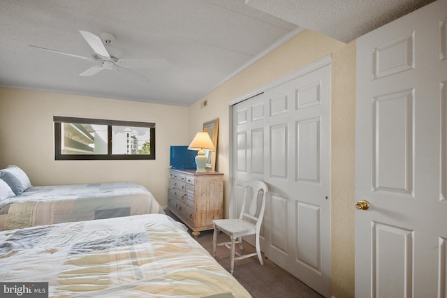 bedroom featuring ceiling fan, dark carpet, a textured ceiling, a closet, and crown molding