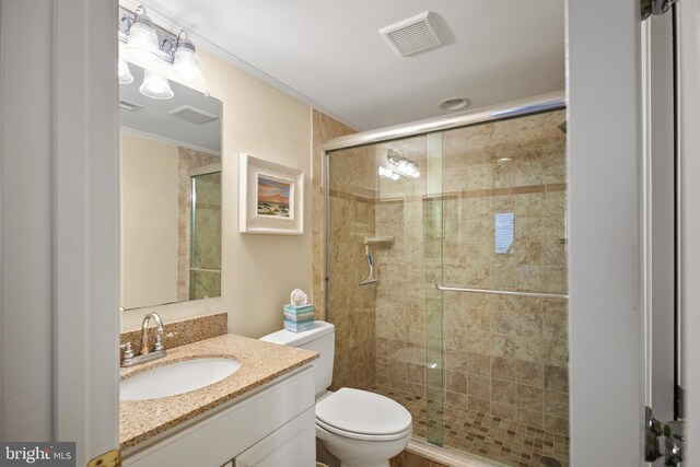 bathroom featuring vanity, a shower with shower door, and toilet