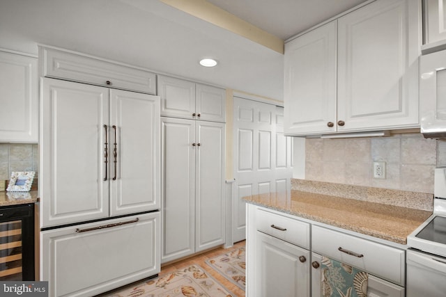 kitchen with electric range, beverage cooler, white cabinets, and tasteful backsplash