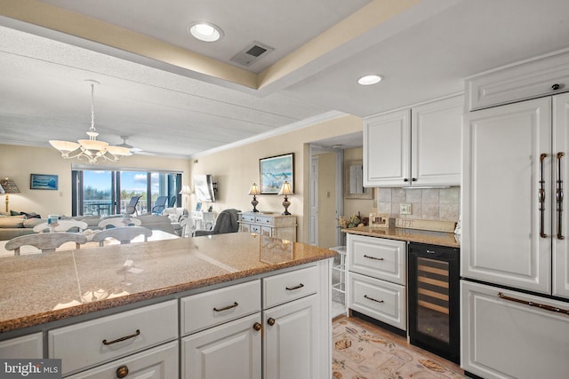 kitchen featuring an inviting chandelier, crown molding, wine cooler, decorative light fixtures, and white cabinets