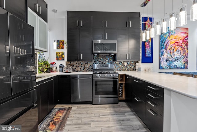 kitchen with tasteful backsplash, pendant lighting, stainless steel appliances, and light hardwood / wood-style flooring