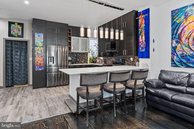 kitchen with a breakfast bar, backsplash, hardwood / wood-style floors, and stainless steel fridge