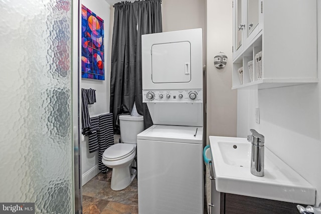 bathroom with stacked washer and dryer, toilet, and vanity