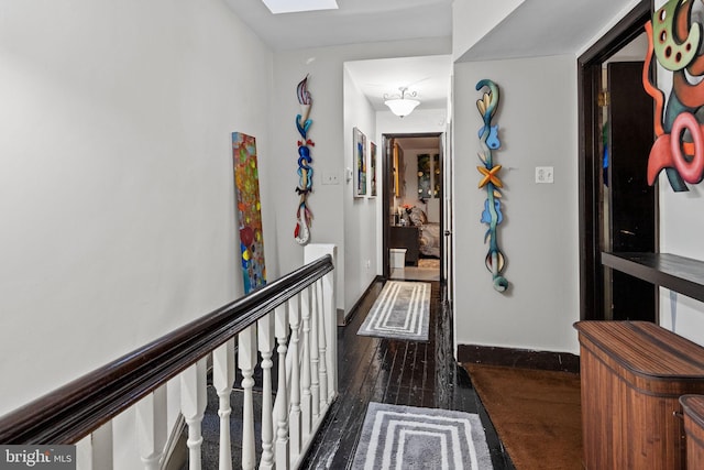 hallway with a skylight and dark wood-type flooring