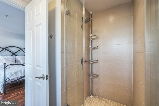 bathroom with a tile shower and wood-type flooring