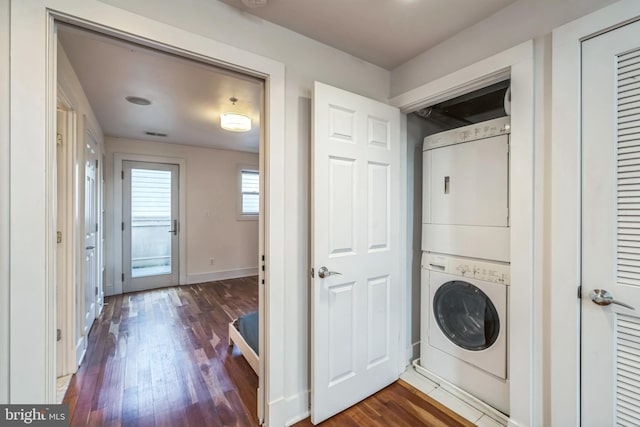 laundry area featuring dark wood-type flooring and stacked washer and dryer