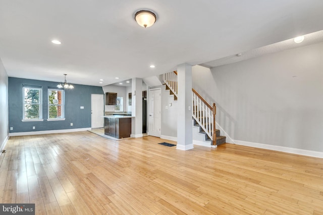 unfurnished living room featuring an inviting chandelier and light wood-type flooring