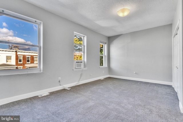 unfurnished bedroom featuring cooling unit, carpet floors, and a textured ceiling