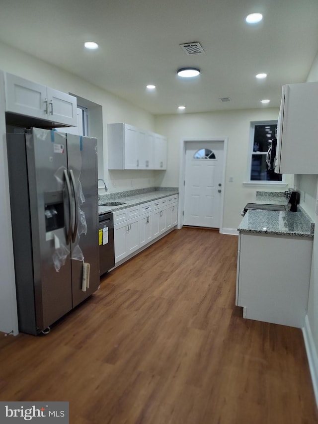 kitchen featuring white cabinetry, light stone countertops, hardwood / wood-style flooring, stainless steel refrigerator with ice dispenser, and sink