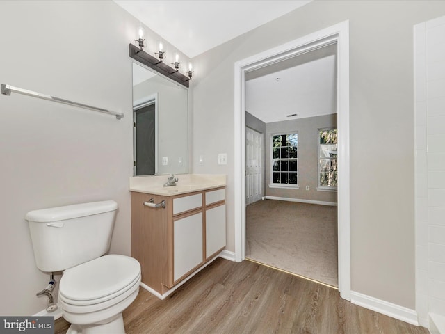 bathroom with toilet, vanity, and wood-type flooring