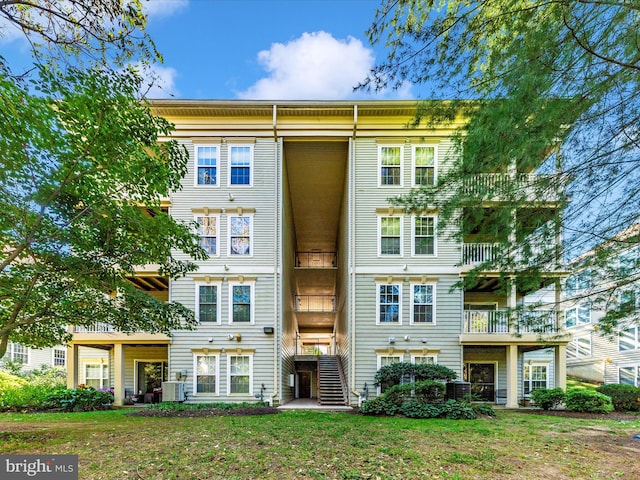 multi unit property featuring central air condition unit, a front lawn, and a balcony