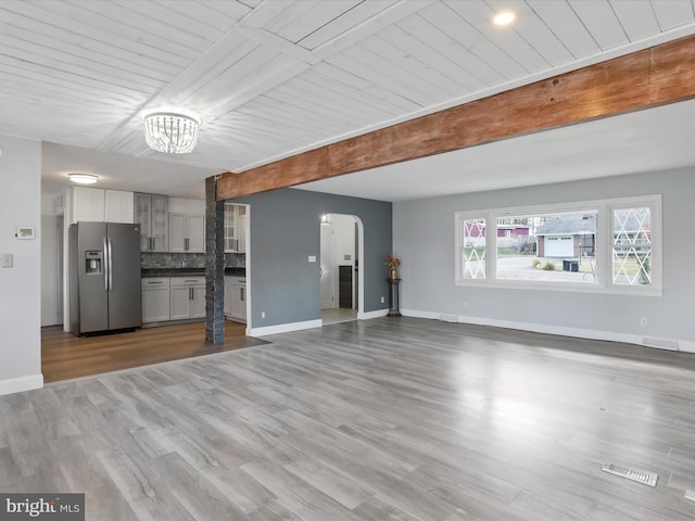 unfurnished living room with a notable chandelier, wood-type flooring, and wood ceiling