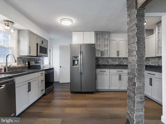 kitchen with backsplash, sink, decorative columns, and appliances with stainless steel finishes