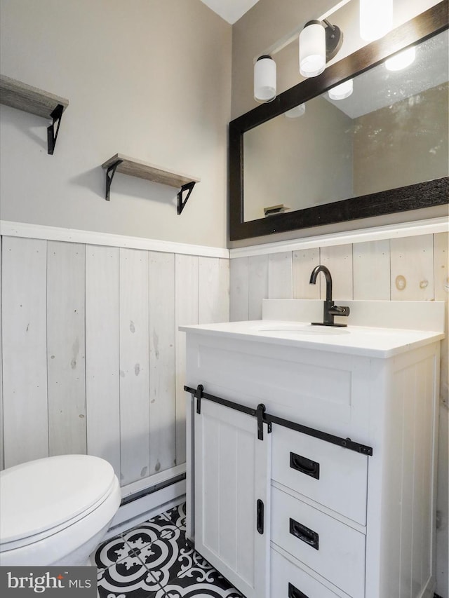 bathroom with vanity, wood walls, toilet, and baseboard heating