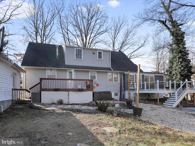 back of house with a hot tub and a wooden deck