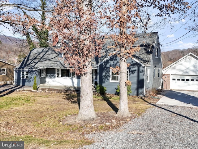 view of front facade featuring a porch, a front yard, an outdoor structure, and a garage