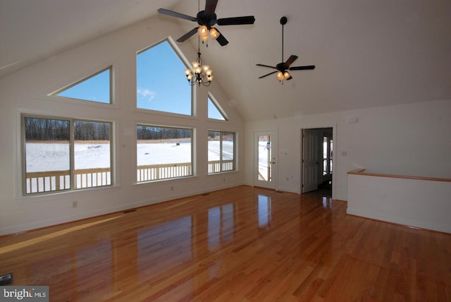 unfurnished living room with hardwood / wood-style floors, high vaulted ceiling, and ceiling fan with notable chandelier