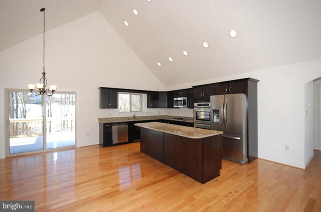 kitchen with stainless steel appliances, high vaulted ceiling, light hardwood / wood-style floors, a kitchen island, and hanging light fixtures