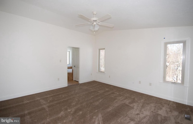 spare room with ceiling fan, dark carpet, and vaulted ceiling