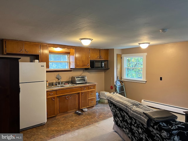 kitchen featuring a wealth of natural light, sink, white fridge, and a baseboard radiator