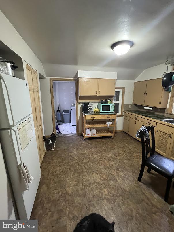 kitchen featuring light brown cabinetry, white appliances, washer / dryer, and sink