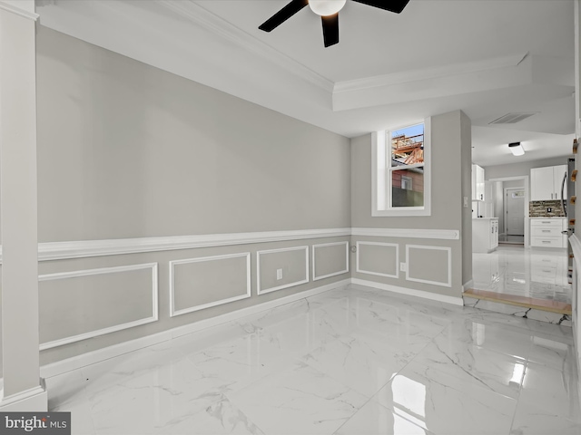 empty room featuring a raised ceiling, ornamental molding, and ceiling fan