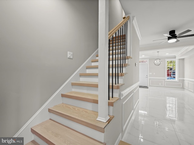 stairs featuring ceiling fan with notable chandelier and ornamental molding