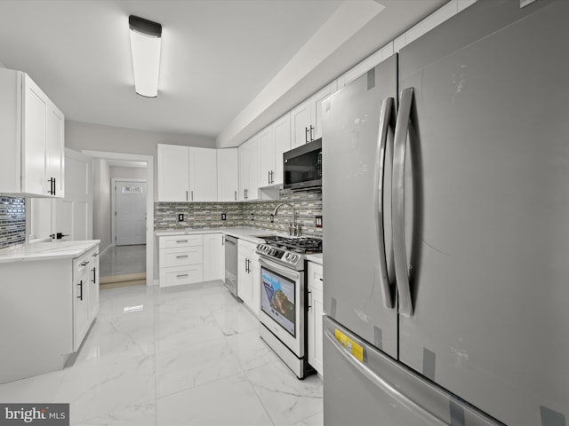 kitchen featuring stainless steel appliances, backsplash, sink, and white cabinetry