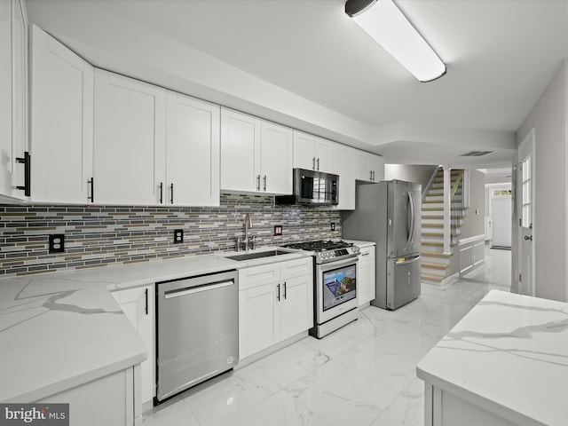 kitchen with light stone countertops, sink, stainless steel appliances, and white cabinets