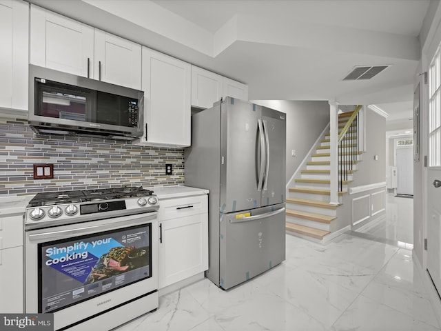 kitchen with stainless steel appliances, white cabinets, and decorative backsplash