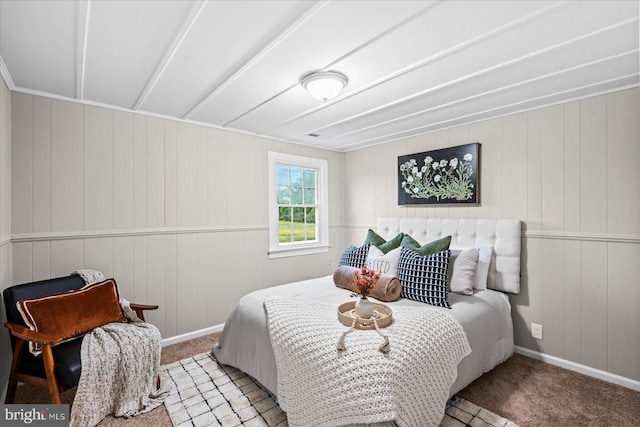 bedroom featuring light carpet and wooden walls