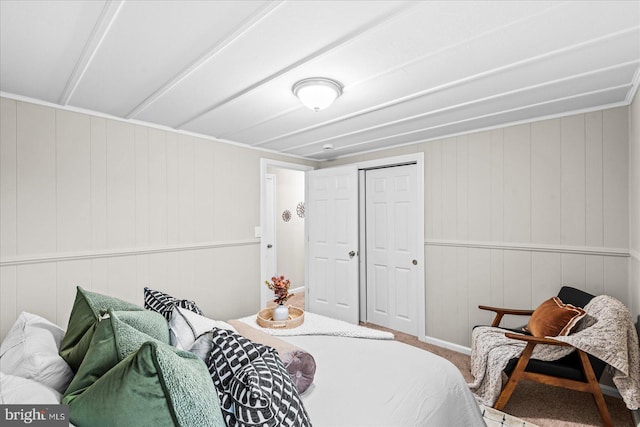 bedroom featuring wooden walls, a closet, and carpet flooring