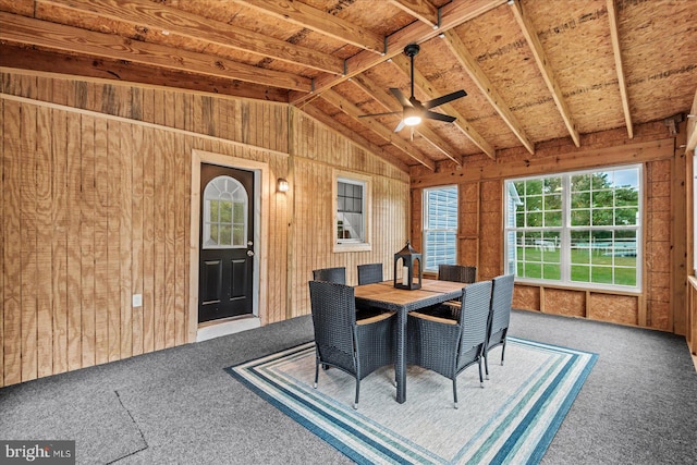 unfurnished dining area featuring carpet floors, lofted ceiling, wood walls, and ceiling fan