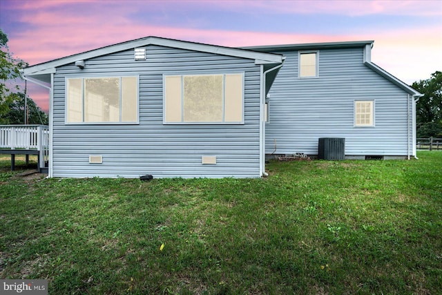 property exterior at dusk with a lawn and a deck