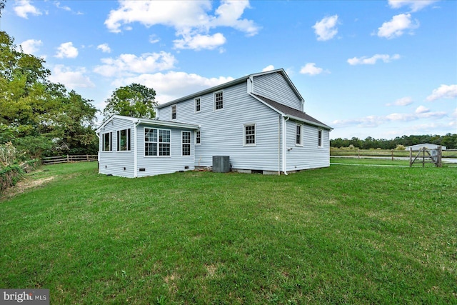 rear view of property with central AC and a yard