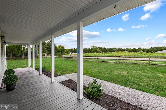 wooden terrace with a rural view and a lawn