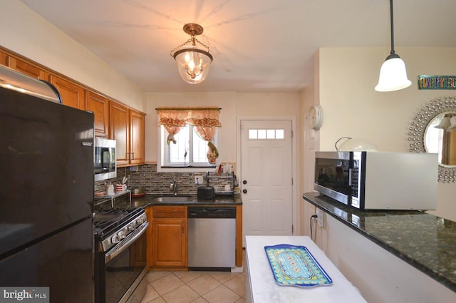 kitchen with pendant lighting, dark stone counters, tasteful backsplash, sink, and stainless steel appliances