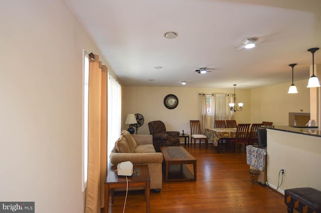 living room with an inviting chandelier, a wealth of natural light, and dark hardwood / wood-style floors