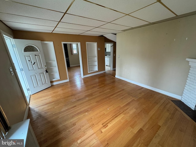 empty room with a drop ceiling, a fireplace, and hardwood / wood-style floors