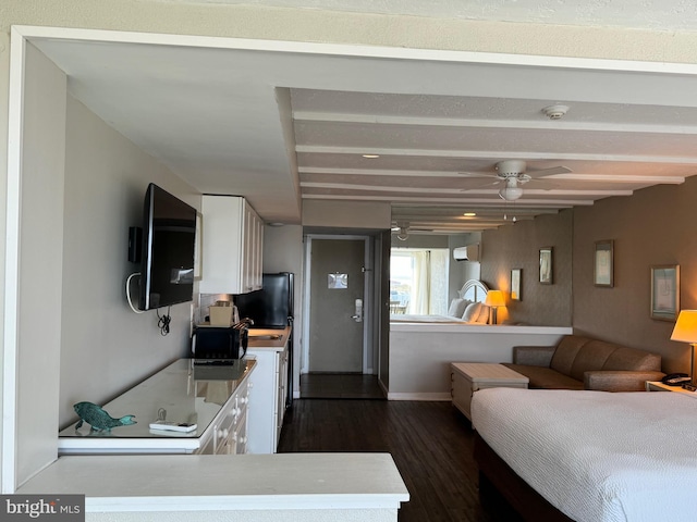 interior space featuring ceiling fan, dark hardwood / wood-style flooring, an AC wall unit, and white cabinetry