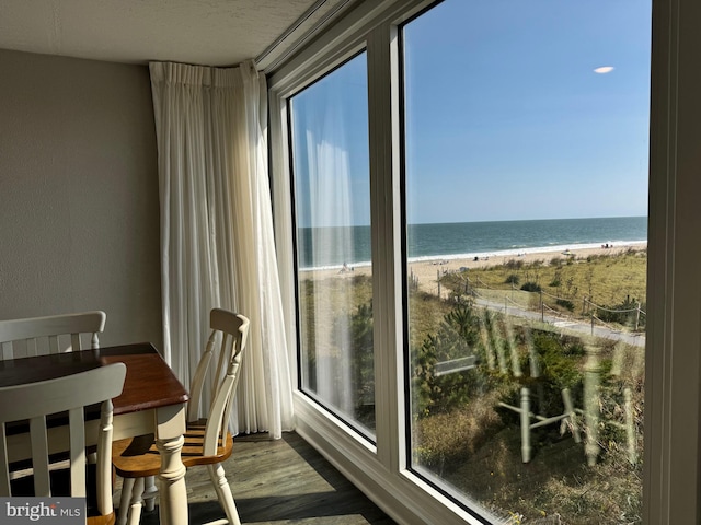 interior space with a water view, a beach view, and hardwood / wood-style floors