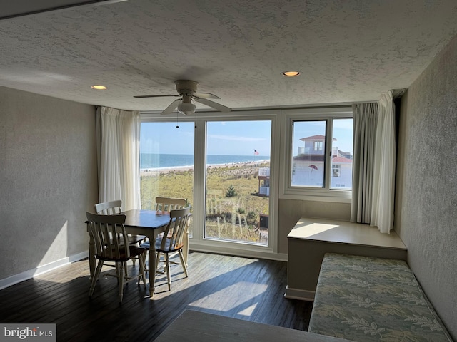 dining space featuring a water view, dark hardwood / wood-style floors, and ceiling fan