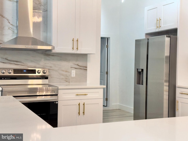 kitchen featuring backsplash, stainless steel appliances, wall chimney range hood, and white cabinets