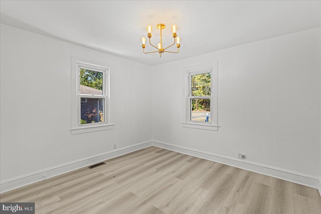 unfurnished room with light hardwood / wood-style floors and a notable chandelier