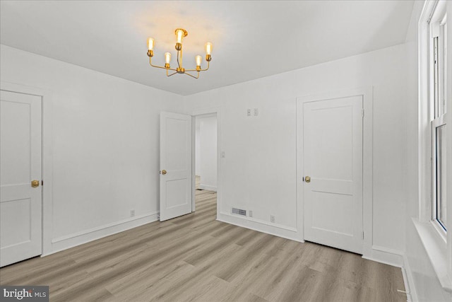 unfurnished bedroom featuring light hardwood / wood-style floors and an inviting chandelier