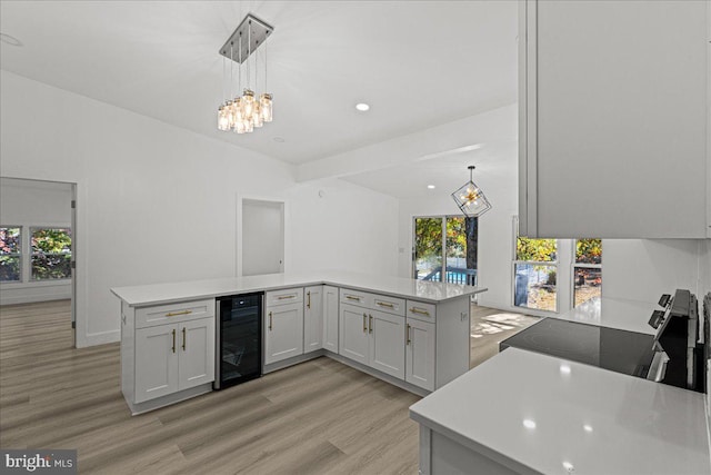 kitchen featuring a wealth of natural light, kitchen peninsula, and beverage cooler