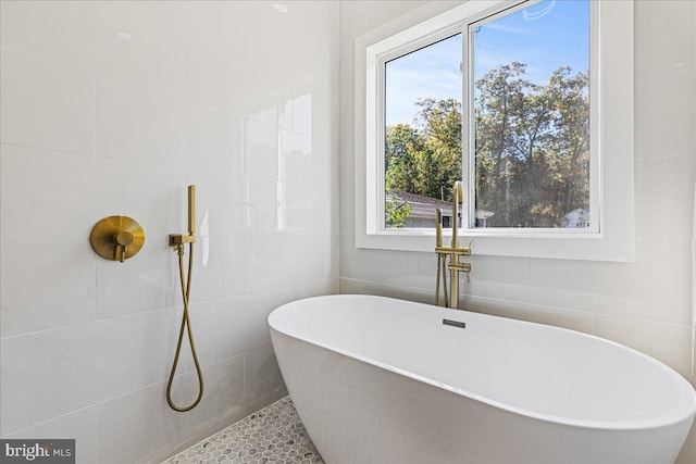 bathroom with a tub to relax in and tile patterned floors