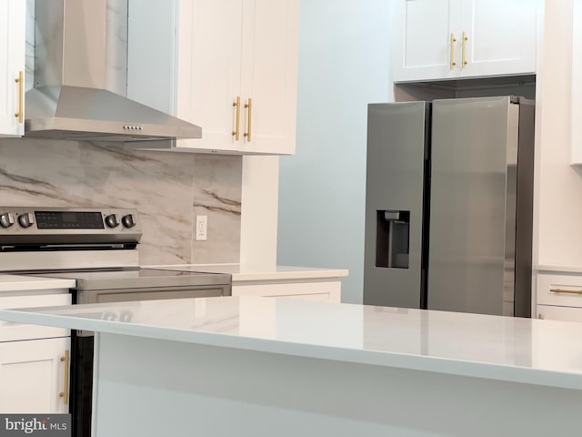 kitchen featuring white cabinetry, stainless steel appliances, wall chimney range hood, and tasteful backsplash