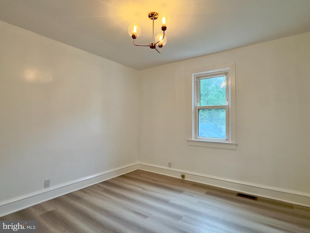 empty room featuring a notable chandelier and hardwood / wood-style flooring